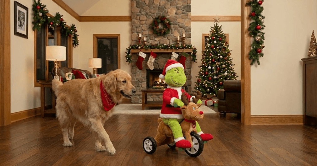 Un Golden Retriever mécontent regarde un jouet Grinch télécommandé s'enfuir avec sa peluche Rudolph.